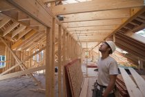 Hispanic carpenter looking at roof on upper floor at a house under construction — Stock Photo