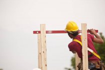Hispanic carpenter measuring chimney posts with a level at a house under construction — Stock Photo