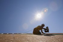 Falegname ispanico che usa una sparachiodi sul tetto di una casa in costruzione — Foto stock