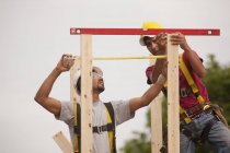 Menuisiers mesurant et nivelant la cheminée d'une maison en construction — Photo de stock