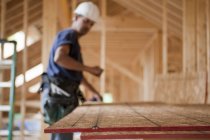 Carpinteiro hispânico estalando uma linha de cordas em um painel de telhado em uma casa em construção — Fotografia de Stock