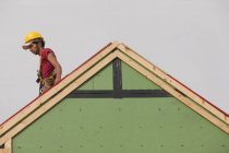 Carpintero hispano trabajando en el techo de una casa en construcción - foto de stock