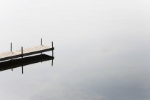 Vue grand angle de jetée vide dans un lac gris calme — Photo de stock