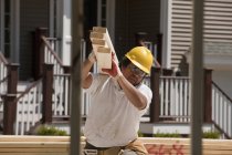 Carpenter carrying planks at a construction site — Stock Photo