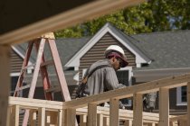 Carpintero con pistola de clavos en el marco en un sitio de construcción de edificios - foto de stock