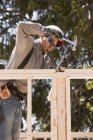 Carpenter hammering a pry bar to adjust studs at a building construction site — Stock Photo