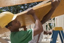 Carpenters lifting a laminated beam at a construction site — Stock Photo
