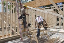 Charpentiers encadrant une maison sur un chantier de construction — Photo de stock