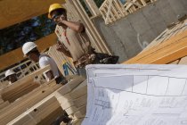 Bauplan mit Zimmerleuten, die ein Haus einrahmen — Stockfoto