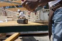 Tischler hält Stahlquadrat auf einer Baustelle — Stockfoto