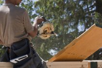 Carpinteiro serrar uma viga em um canteiro de obras — Fotografia de Stock