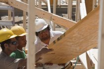 Carpinteros levantando una viga laminada en un sitio de construcción - foto de stock