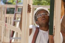 Carpintero levantando una viga en una obra de construcción - foto de stock