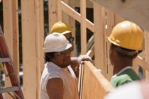 Carpenters lifting beam at a building construction site — Stock Photo