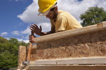 Carpinteiro usando martelo de enquadramento em uma moldura da casa — Fotografia de Stock