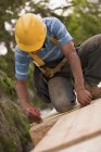 Carpinteiro usando fita métrica no piso em um canteiro de obras de construção — Fotografia de Stock