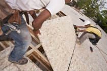 Falegnami che installano un pannello truciolare in un cantiere edile — Foto stock