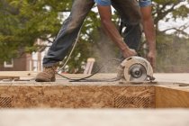 Carpenter sawing a particle board at a building construction site — Stock Photo