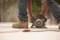 Cropped image of Carpenter sawing a board at a building construction site — Stock Photo