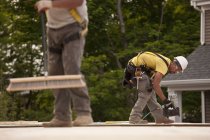 Carpenters using broom and nail gun at a construction site — Stock Photo