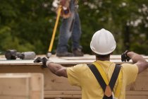 Carpenter putting a particle board in place at a building construction site — Stock Photo