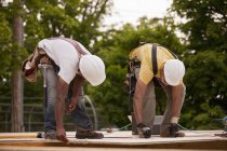 Carpenters working on a particle board at a building construction site — Stock Photo