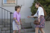 Женщина с церебральным параличом приветствует свою сестру на улице — стоковое фото