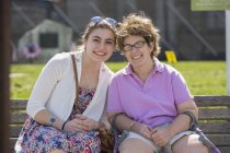 Женщина с церебральным параличом сидит со своей сестрой в парке — стоковое фото