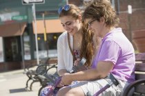 Femme atteinte de paralysie cérébrale assise avec sa sœur sur un banc dans une ville — Photo de stock