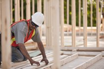 Charpentier travaillant sur un cadre de maison sur un chantier de construction — Photo de stock