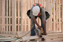 Carpenter sawing wood for house framing at a building construction site — Stock Photo