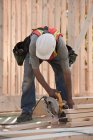 Тесляр розпилює деревину для обрамлення будинку на будівельному майданчику — стокове фото