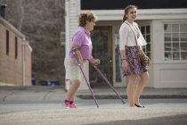 Frau mit Zerebralparese und Krücken läuft mit ihrer Schwester in der Stadt — Stockfoto