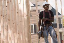 Menuisier travaillant avec un marteau et un pistolet à clous sur un chantier de construction — Photo de stock