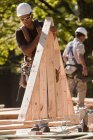 Carpinteiros segurando uma palheta de cobertura em um canteiro de obras — Fotografia de Stock