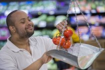Homem com Síndrome de Down pesando tomates em uma mercearia — Fotografia de Stock