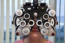 Mujer examinándose los ojos con un horopter en la clínica - foto de stock