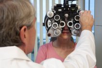 Oftalmologo che esamina un occhio femminile con un phoropter — Foto stock