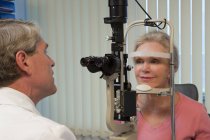 Ophthalmologist examining a woman's eyes with a slit lamp — Stock Photo