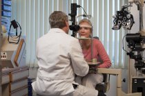 Офтальмолог, який вивчає жіночі очі з лампою для щілин — стокове фото