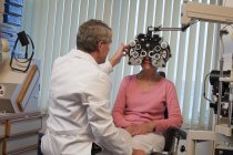 Ophtalmologiste examinant les yeux d'une femme avec un phoropter — Photo de stock
