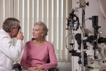 Офтальмолог, який вивчає жіночі очі з прямим офтальмоскопом — стокове фото