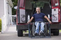 Mann mit Querschnittslähmung steigt im Rollstuhl in seinen barrierefreien Van — Stockfoto