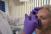 Oftalmólogo que administra una inyección de Botox a un paciente - foto de stock