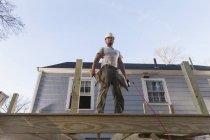 Hispanic carpenter using nail gun on home deck construction — Stock Photo