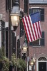 Laternen an einer Wand mit amerikanischer Kolonialflagge im Hintergrund, Eichelstraße, Leuchtturmhügel, Boston, massachusetts, usa — Stockfoto