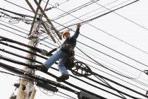 Kommunikationsarbeiter an einem Strommast zur Befestigung von Klemmen zur Unterstützung des Kabels — Stockfoto
