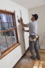 Carpintero hispano usando nivel para marcar corte para nueva puerta de cubierta en casa - foto de stock