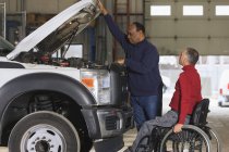Técnico de manutenção automotiva e supervisor com lesão medular na garagem caminhão — Fotografia de Stock