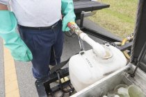 Tecnico di controllo dei parassiti che aggiunge acqua al contenitore chimico in camion — Foto stock